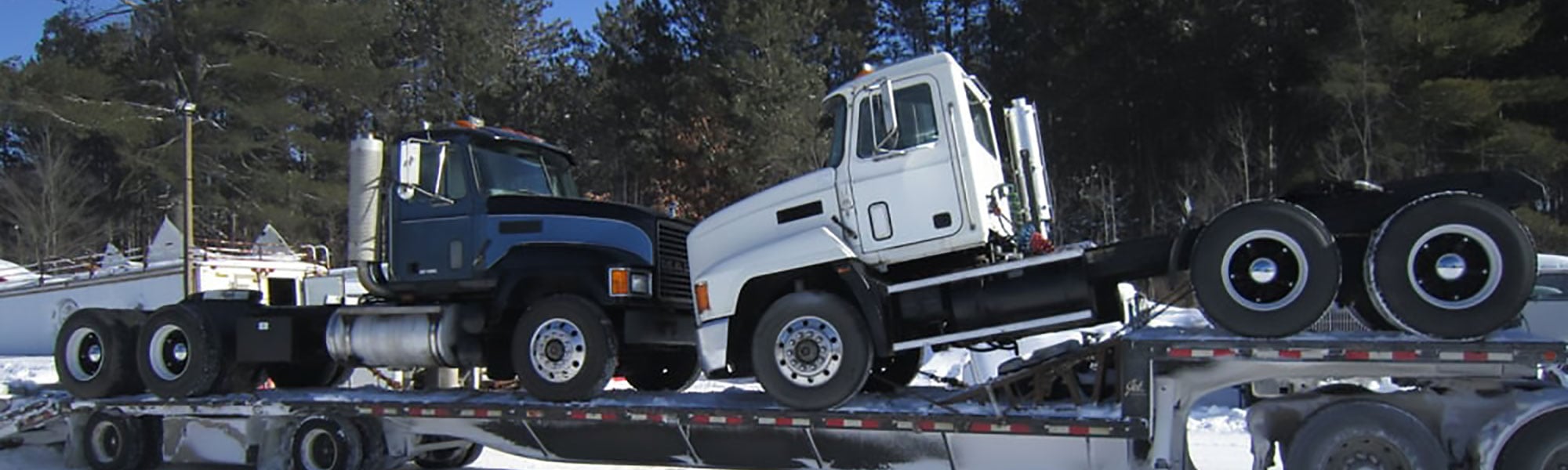 Day cab trucks on a low boy trailer